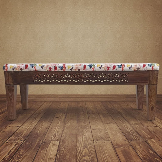 A wooden bench with off white color cushion covered in soft fabric with a floral pattern.