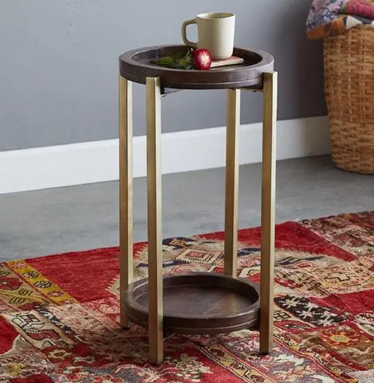 A round side table with a mango wood top in a walnut finish and gold metal legs. 