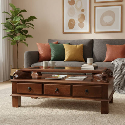 A rectangular brown Asgil coffee table made of mango wood with three drawers and carved elephant details on the sides.
