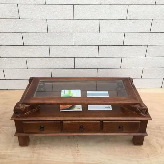 rectangular brown Three drawer and carved elephant details on the sides Asgil coffee table made in Solid mango wood and glass on the top. 