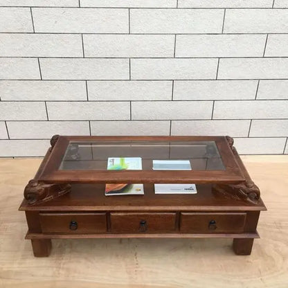 rectangular brown Three drawer and carved elephant details on the sides Asgil coffee table made in Solid mango wood and glass on the top. 