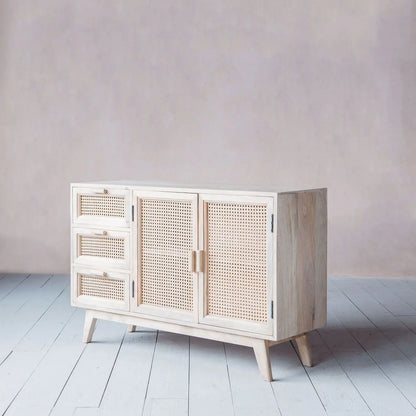 Wooden sideboard with rattan doors and drawers in a minimalistic room. 