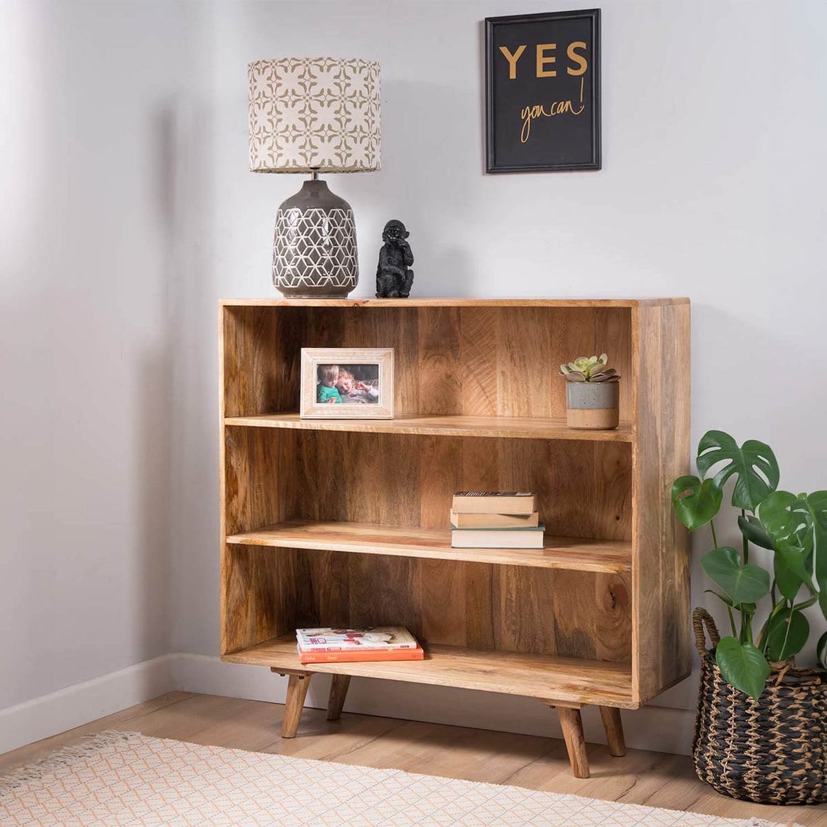 A solid wood three-tier bookshelf with tapered legs.