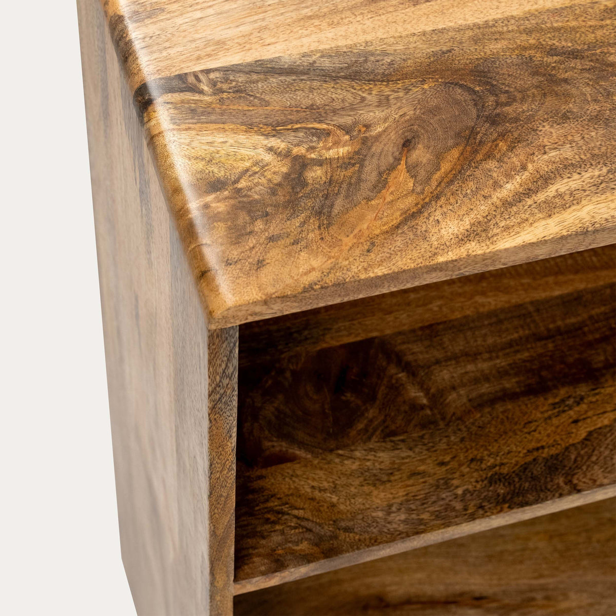 Close-up of a wooden furniture piece showing the corner of a tabletop and an open shelf with rich brown wood grain patterns.