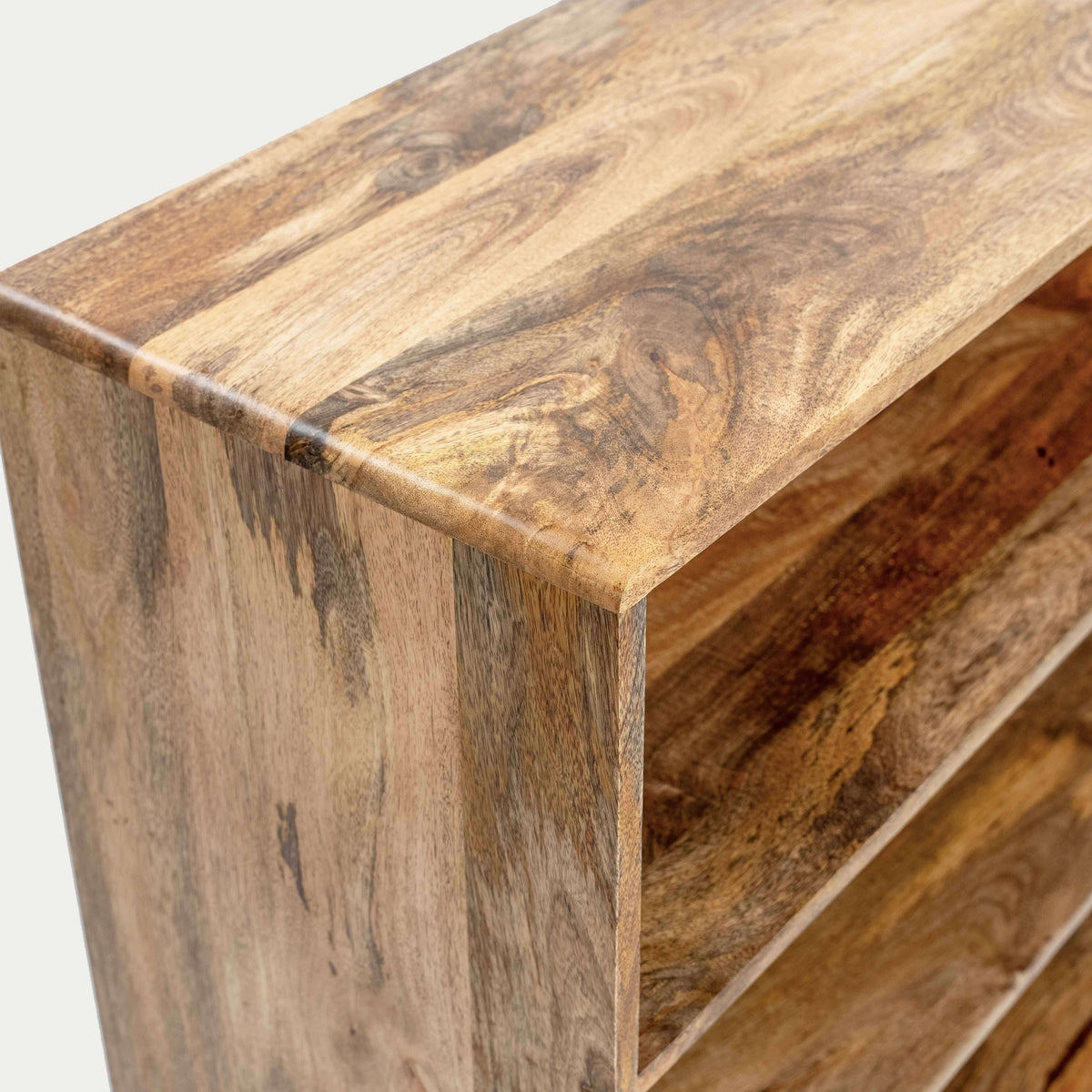 a wooden shelf or cabinet corner showing natural wood grain and a slatted open shelf space.