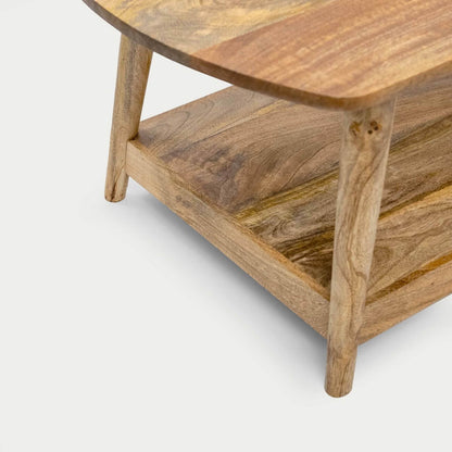 Close-up of a wooden table corner showing a curved top, natural wood grain, legs, and a lower shelf.