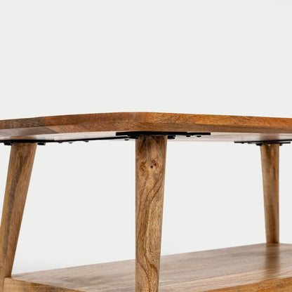 Close-up of a wooden table or shelf unit with natural wood grain, angled legs, and black metal brackets under the tabletop.