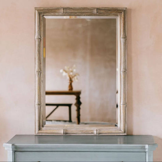 A rectangular wall mirror with a distressed bamboo-style frame.
