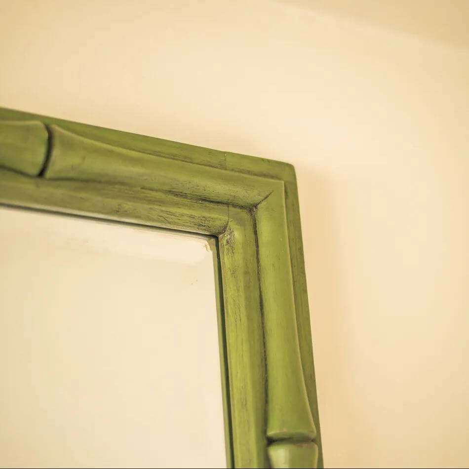 Close-up of a bamboo-style mirror frame in a muted olive green finish.