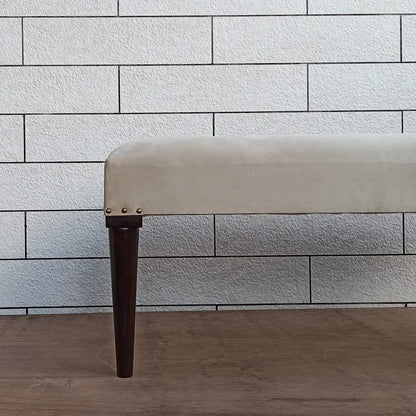 Beige carvin bench with dark round wooden legs.