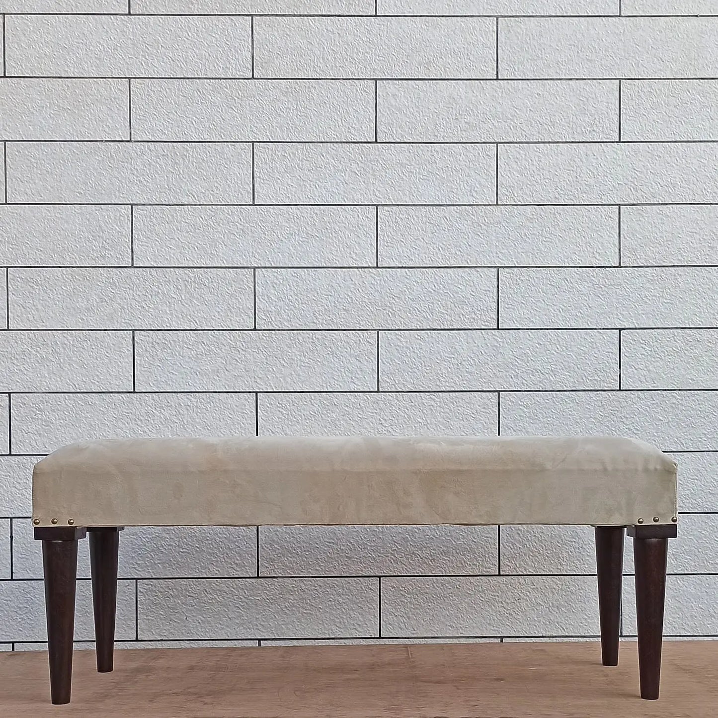 Beige bench with dark round wooden legs.