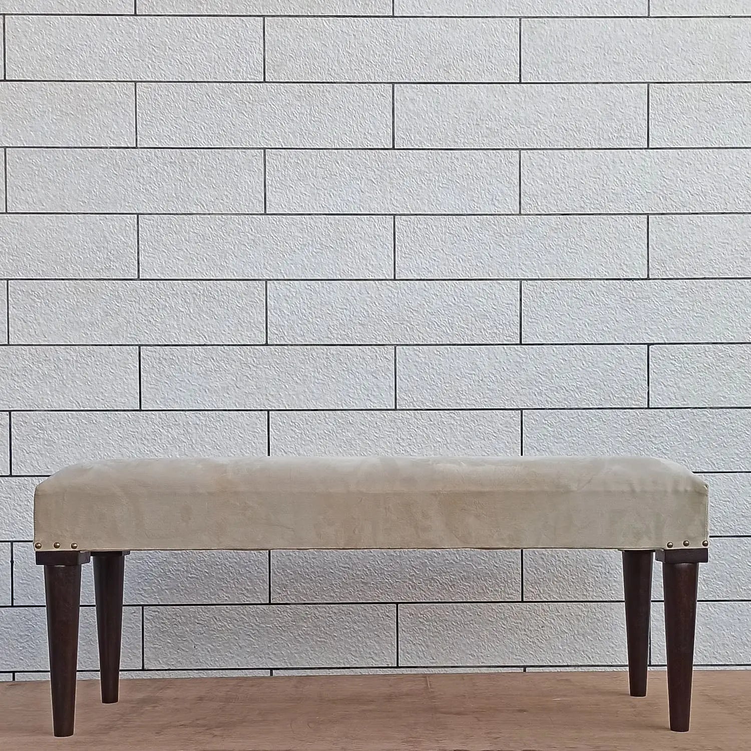 Beige bench with dark round wooden legs.