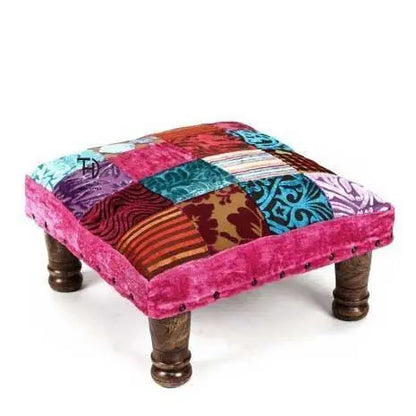 Colorful patchwork footstool with wooden legs.
