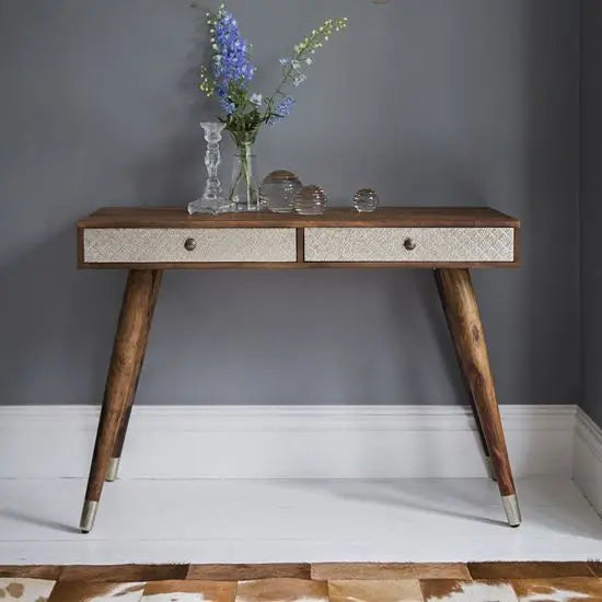 A Clazzer study table made of solid wood with a natural stain finish, featuring two storage drawers, brass knobs, and an Embossed metal sheet on the drawer front.