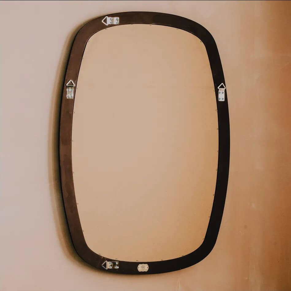 A dark brown metal wall mirror with a rounded rectangular shape and decorative silver metal brackets at the corners.