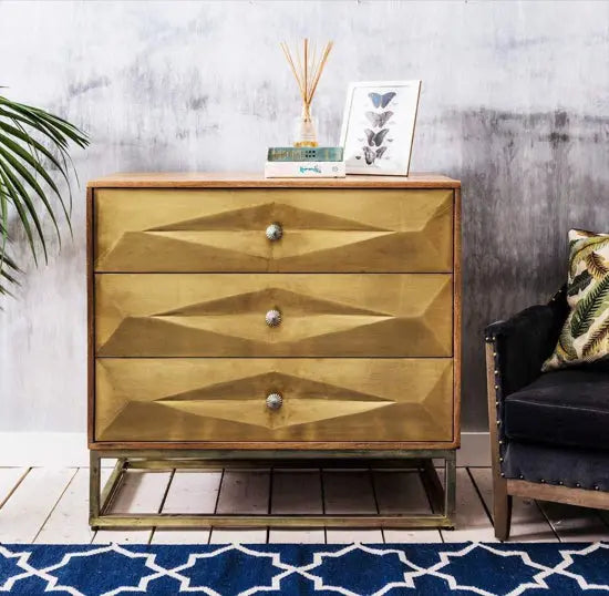 A brass-painted chest of drawers with three drawers, featuring a geometric design on the drawer fronts. Export Quality furniture product.