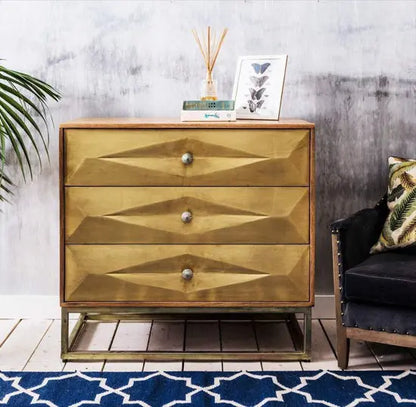 A brass-painted chest of drawers with three drawers, featuring a geometric design on the drawer fronts. Export Quality furniture product.