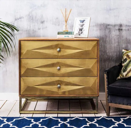 A brass-painted chest of drawers with three drawers, featuring a geometric design on the drawer fronts. Export Quality furniture product.