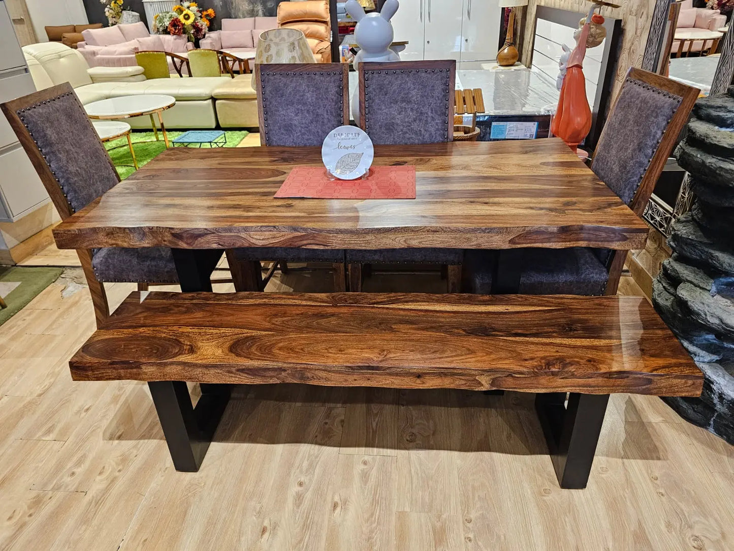 Wooden dining table with chairs and a bench in a showroom setting or dining room.