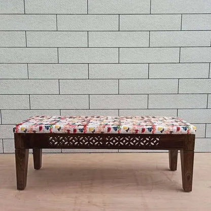 Bench topped with colorful patterned cushion.