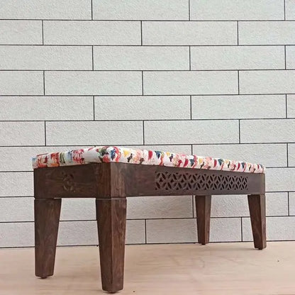 A wooden bench with dark finish and carved details on sides.