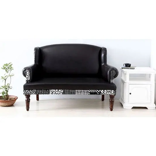 A black Maharani 2 seater sofa with rexine and velvet touch fabric, featuring round front legs with walnut color.