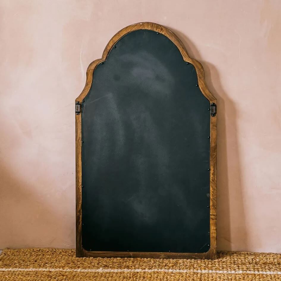 An arched black chalkboard with a rustic, weathered brown wooden frame, leaning.