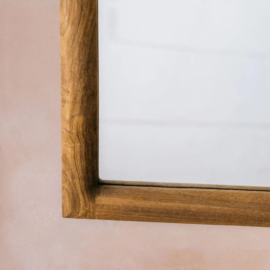 Close-up of a wooden mirror frame corner with a warm medium-brown finish.
