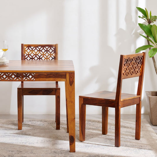 A wooden dining chairs with geometric cutout backs.