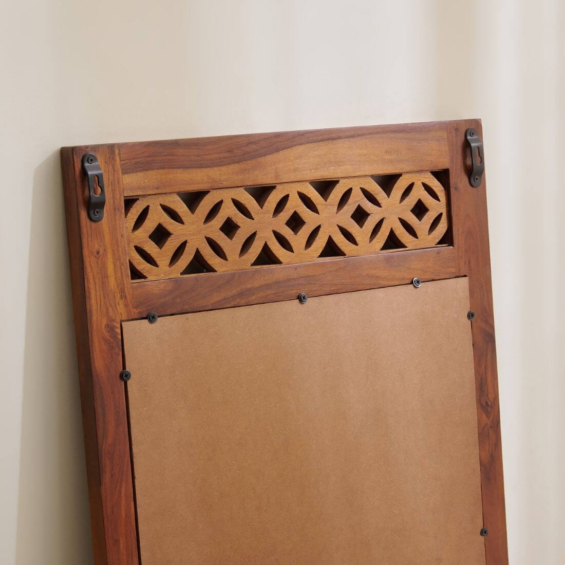 A wooden wall-mounted board or panel with a decorative cutout pattern near the top and a plain brown backing on the lower section.