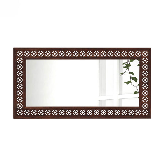 A rectangular wall mirror with an ornate dark brown wooden frame featuring a repeating geometric cutout pattern.