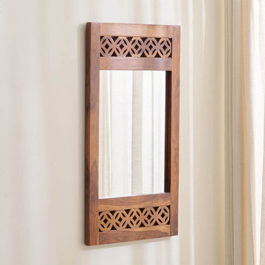 A vertical rectangular wooden wall mirror with decorative geometric cutout patterns at the top and bottom.