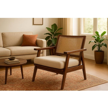 A mid-century modern wooden armchair with a woven cane backrest and cream cushions, styled in a warm, sunlit living room next to a beige sofa.