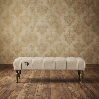 An upholstered cream fabric coffee table with tufted design and bottle-shaped turned wooden legs.