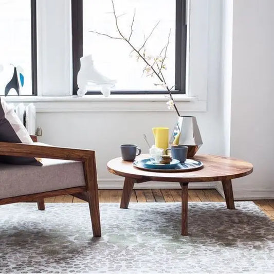 A low-height, round coffee table made of sheesham wood with knockdown legs.