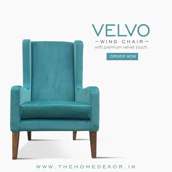 A luxurious olive green velvet wing chair with a sturdy wooden structure, featuring a high back and winged armrests.