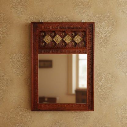 A vintage mirror frame with a brown honey-like finish and decorative elements in a geometric pattern.