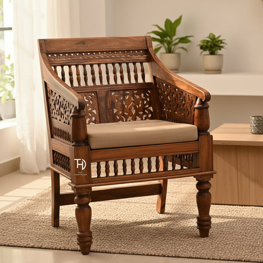 A wooden chair with intricate carvings and a honey-colored finish, featuring a spindle back design and ornate armrests.