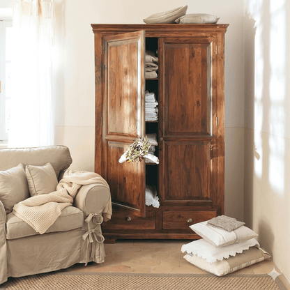 A vintage wooden wardrobe with two doors and drawers. The wardrobe is open, revealing hanging clothes and storage space.
