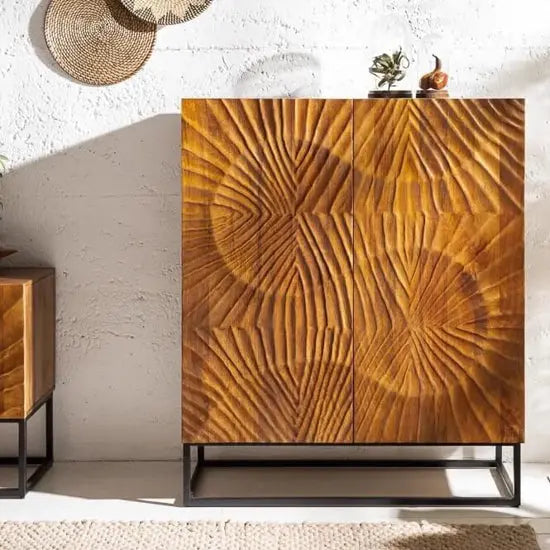 A wooden sideboard with a sleek metal base, featuring intricate carvings on the doors with metal base.