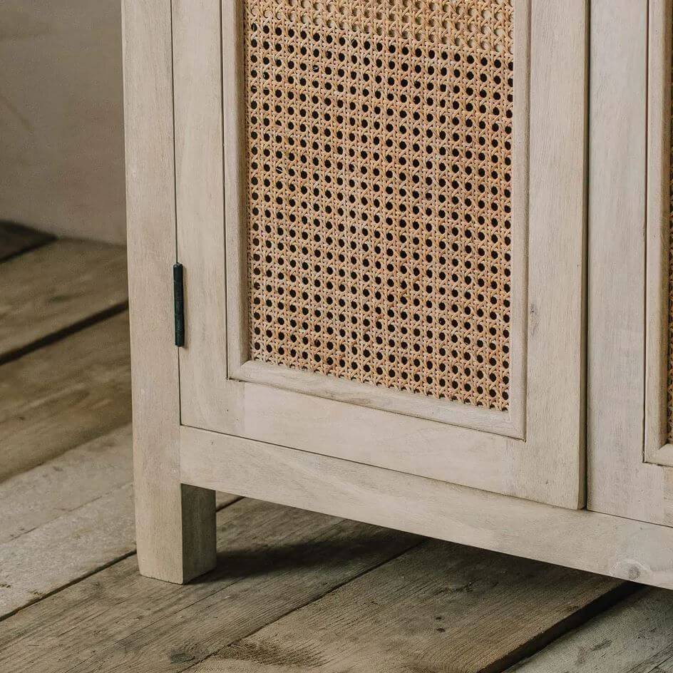 Close-up of a light beige wooden cabinet with woven cane panels on the doors mae in solid mango wood.