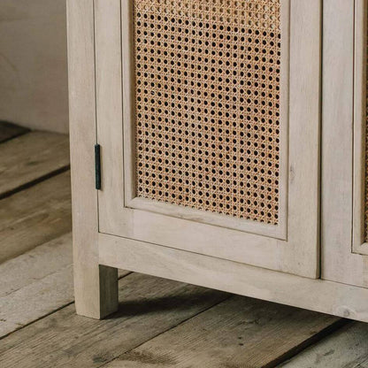 Close-up of a light beige wooden cabinet with woven cane panels on the doors mae in solid mango wood.