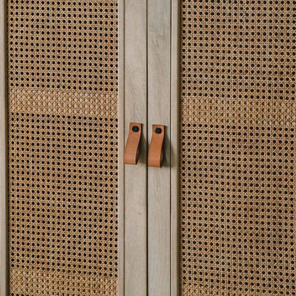 Close-up of a cabinet door with woven cane or rattan panels and two small rectangular leatharite handles.