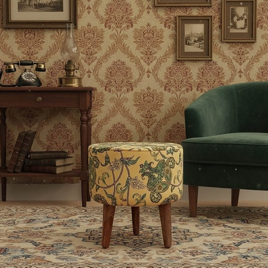 A yellow upholstered pouf with a floral pattern, on three wooden legs.