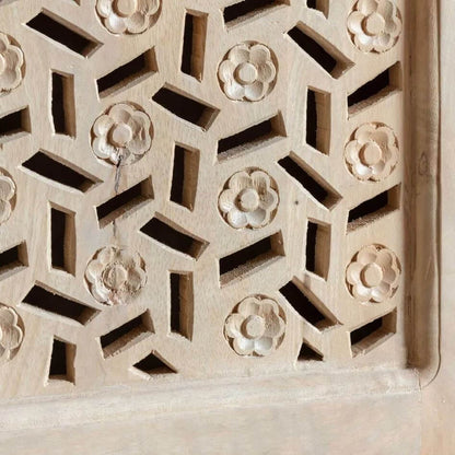 Close-up of a light natural wood carved screen or wall panel with repeating floral and geometric cutout patterns.