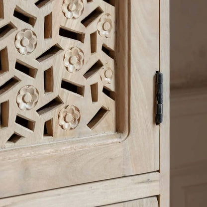 Close-up of a light natural wood cabinet door with intricate geometric cutouts and carved floral motifs, featuring a black metal hinge.